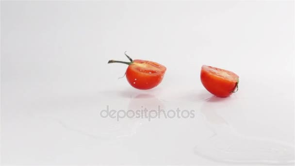 Dos mitades de roturas de tomate golpeando la superficie blanca — Vídeos de Stock