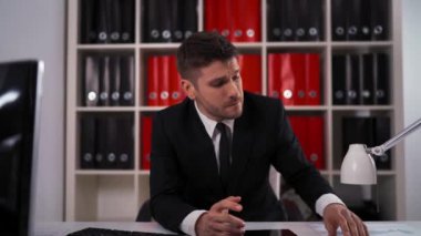 Genç işadamı ofiste çalışmalar sırasında baş ağrısına sahip