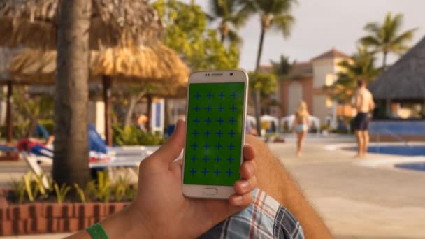 Hombre relajarse en el baño de sol en la piscina con el uso de teléfono móvil — Vídeos de Stock