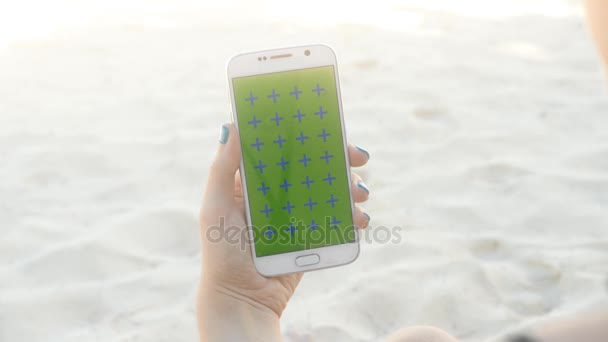 Mano de hombre sosteniendo blanco móvil vertical en la playa — Vídeo de stock