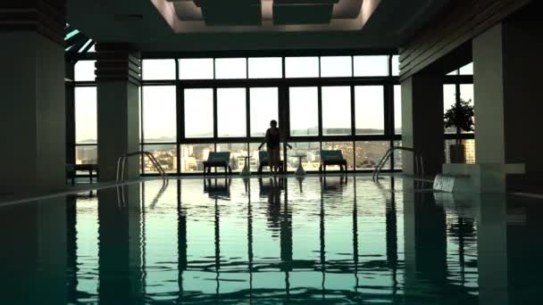 Молодая женщина прыгает в бассейн в отеле — стоковое видео