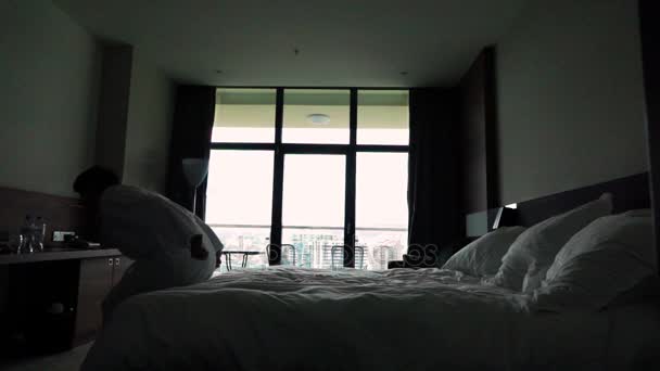 Счастливый молодой человек прыгнул на кровать в отеле в халате — стоковое видео