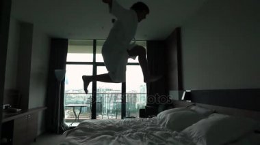 Mutlu genç adam yatakta bornoz Otel'de atlama