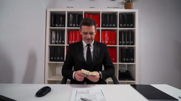 Jeune homme d'affaires beau en costume noir et cravate compter les dollars — Video