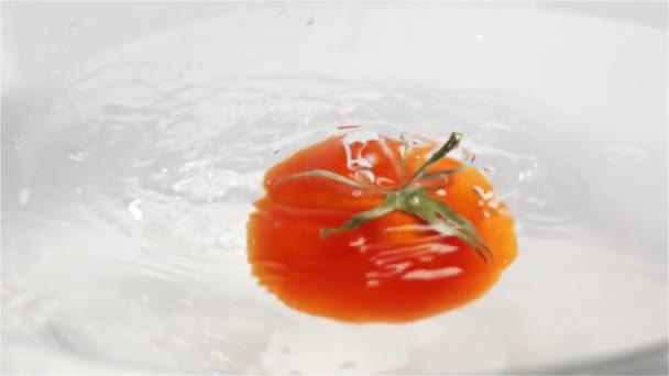 Un pomodoro rosso maturo con foglie verdi cade sott'acqua — Video Stock