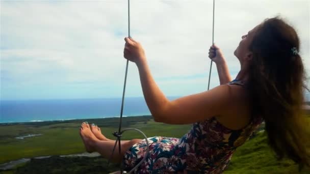 Женщина на качелях и голубое небо с океаном и горой — стоковое видео