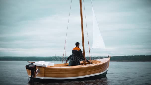 Houten zeilboot met twee mannen probeert in te stellen van de mast — Stockvideo