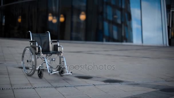 Invalid wheelchair rolling near modernn building. — Stock Video