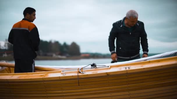 Mistr a jeho asistent pracují na dřevěné plachetnici na řece — Stock video