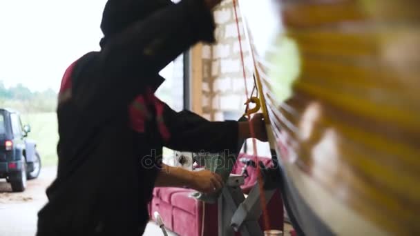 Master and assistant try to movie sailboat in garage workroom. — Stock Video