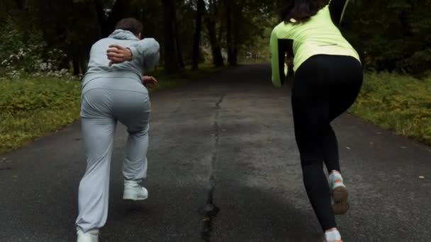 Fitness pár készen áll a fa gyalogjárda egy szabadtéri park rajthoz a futóverseny jelentenek. — Stock videók