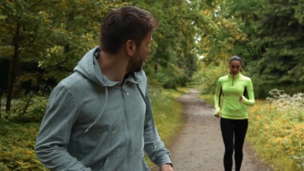 Joven corredor chico correr con mujer cae detrás en parque — Vídeos de Stock