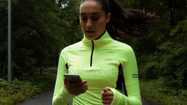 Happy fit woman runner look at her mobile phone while running — Stock Video