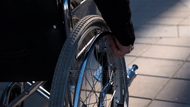 Вид сзади на человека в инвалидной коляске рядом с бизнес-центром с фокусом на руке — стоковое видео