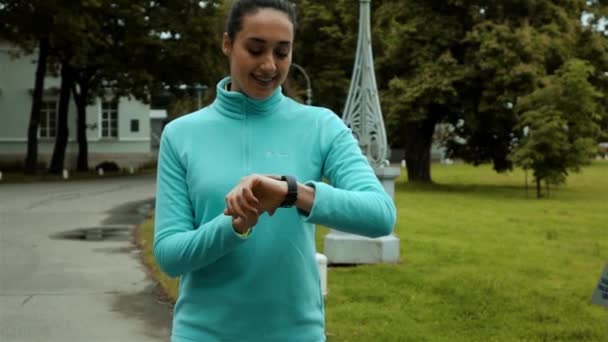 Corredor de la mujer usando rastreador de fitness reloj inteligente en bosque de otoño verde — Vídeo de stock