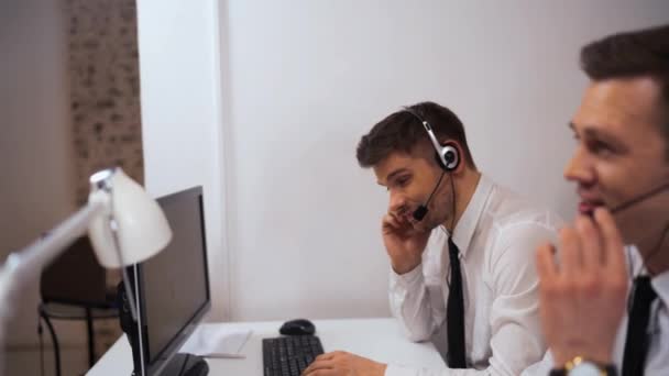 Twee mannelijke oproep centrum ondersteunen specialist in gesprek met klanten door headsets. — Stockvideo