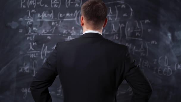 Vista posteriore dell'uomo contro lavagna con equazioni formula matematica — Video Stock