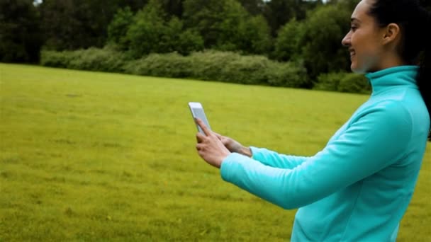 Female jogger standing on a nature trail and taking a smiling selfie with her phone — Stock Video