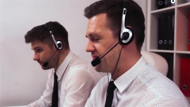 Zwei Männer mit Kopfhörern im Gespräch über Anrufzentrale — Stockvideo