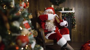 Noel Baba eski kırmızı ipek albümde yakın oyuncak ve ışıklar ile Noel ağacı çekerek