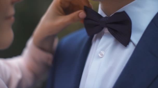 Невеста поправляет бабочку галстук жениха — стоковое видео