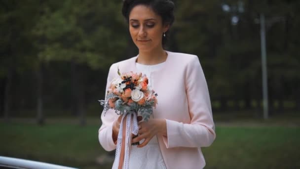 Novia elegante con un hermoso ramo de flores en el parque — Vídeos de Stock