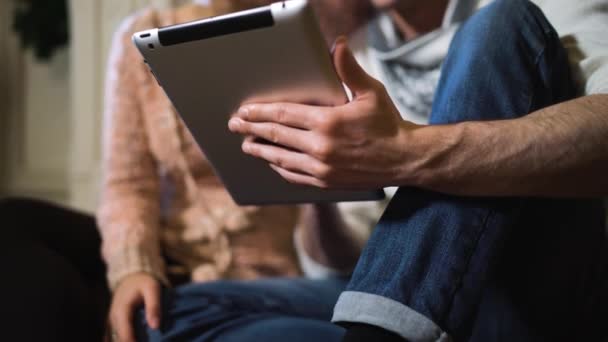 Ung man visar något till sin flickvän på tablet Pc på jul. — Stockvideo