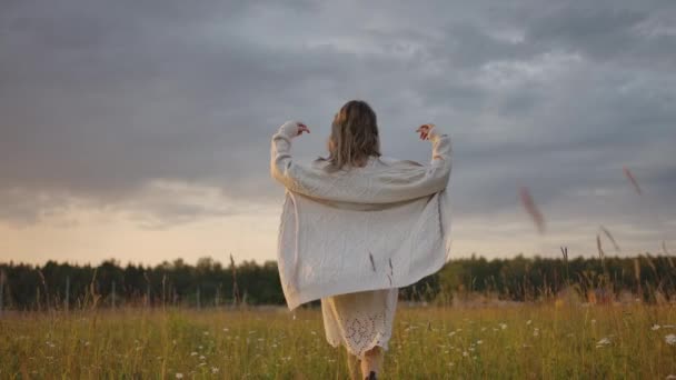 Mujer poniéndose una chaqueta larga y cálida en el prado — Vídeo de stock