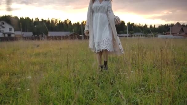 Dreamy woman walking and spinning on grass in evening — ストック動画