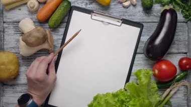 Malzeme listesine işaret eden kalemle yüzsüz aşçı