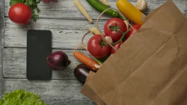 Овощи крутятся рядом со смартфоном и продуктами — стоковое видео