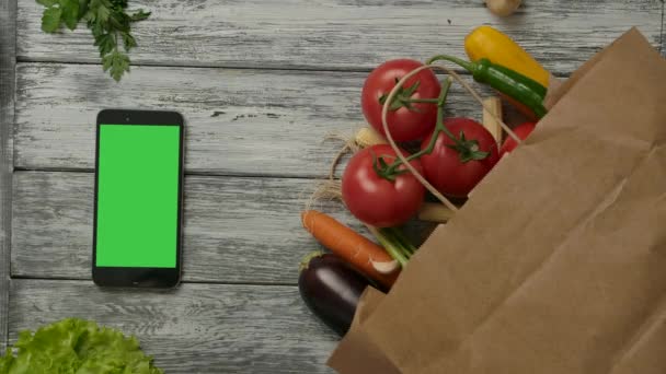 Tomate rolando perto de legumes e smartphones — Vídeo de Stock