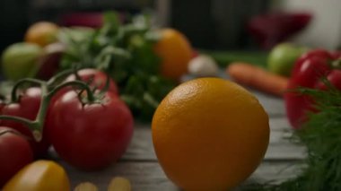 İsimsiz biri turuncuyu organik sebzelerin arasından yuvarlıyor.