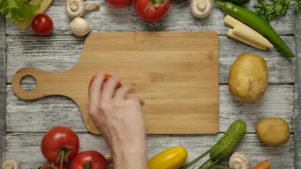 Tomate tourbillonnante à la main masculine sur planche à découper. — Video