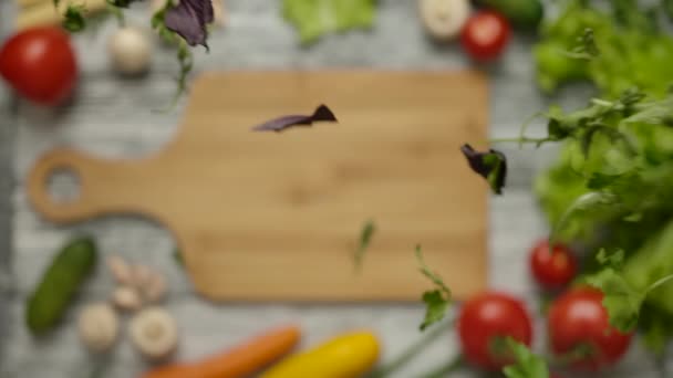 Folhas de salsa e manjericão caindo em tábua de corte de madeira — Vídeo de Stock