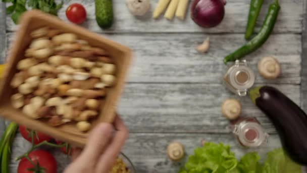 Kok het plaatsen van houten kom van noten op tafel met verschillende ingrediënten — Stockvideo