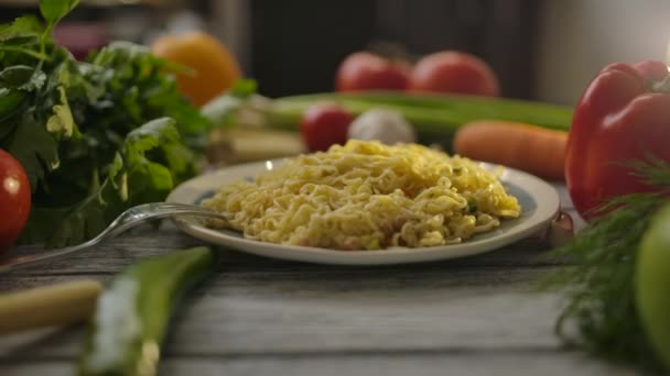 Placa con fideos chinos baratos en medio de verduras maduras en mesa de madera — Vídeo de stock