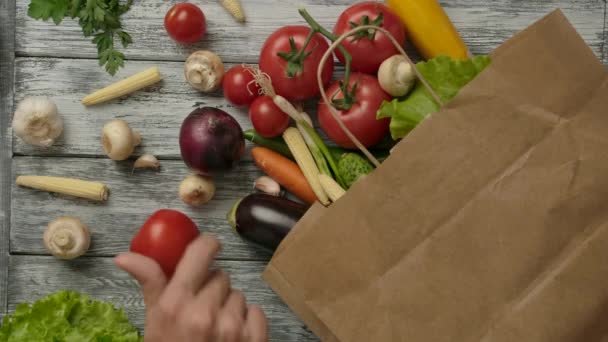 Mans hand spinning tomato near groceries and vegetables sack — Stock Video