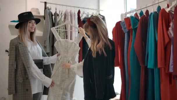 Feliz damas jóvenes discutiendo el diseño del vestido en el showroom del centro comercial moderno . — Vídeos de Stock