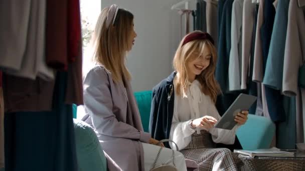 Vrolijke vrouwen discussiëren online catalogus op bank in de winkel. — Stockvideo