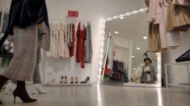Satıcı, müşteriye açık modern sergi salonunda şık kıyafetler seçmesinde yardımcı oluyor.