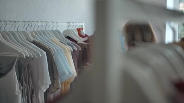 Mujer joven eligiendo ropa en la tienda. — Vídeos de Stock