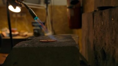 Zanaatkar, yüksek sıcaklıklarda bir gaz ocağı kullanarak parçayla çalışıyor.. 