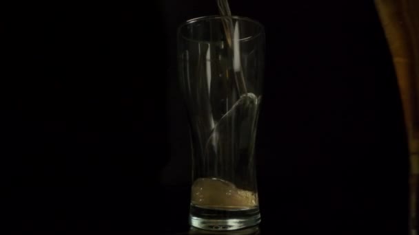 Пиво медленно наливается в стеклянную чашку . — стоковое видео