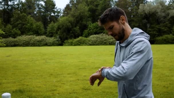 Hombre corriendo en los bosques verdes del parque de formación y mirar los relojes inteligentes — Vídeos de Stock