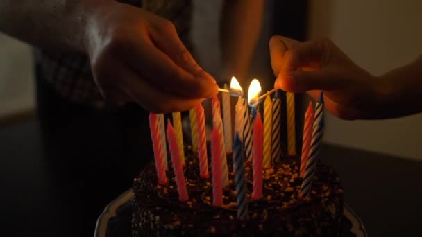 Mulher e homem acende velas no bolo de aniversário saboroso. Preparecimento para festa . — Vídeo de Stock