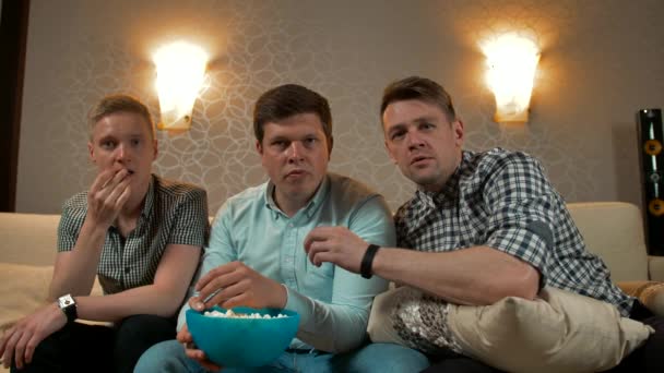 Trzech młodych mężczyzn przerażonych filmem w telewizji — Wideo stockowe