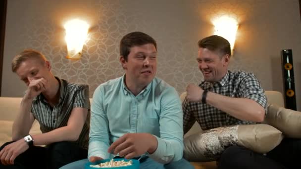 Счастливые трое мужчин смотрят комедийный фильм по телевизору — стоковое видео