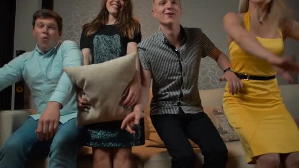 Jovens que caem no sofá para assistir TV com travesseiro ou almofada — Vídeo de Stock