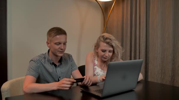 Atraente cara e menina sentar no coucand loja on-line com cartão de crédito no notebook laptop . — Vídeo de Stock